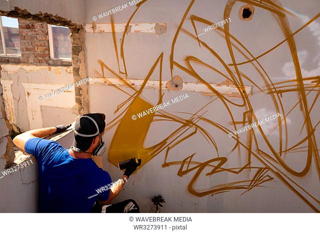 Graffiti artist spray painting weathered wall