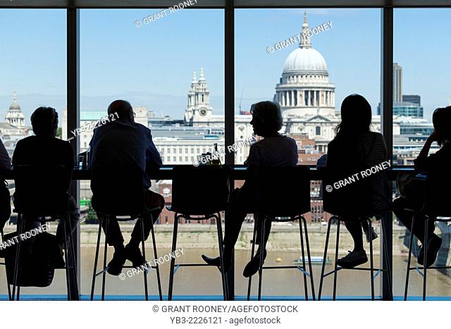 People sit looking at the London skyline from the 3rd floor cafe at Tate Modern art gallery, London, England