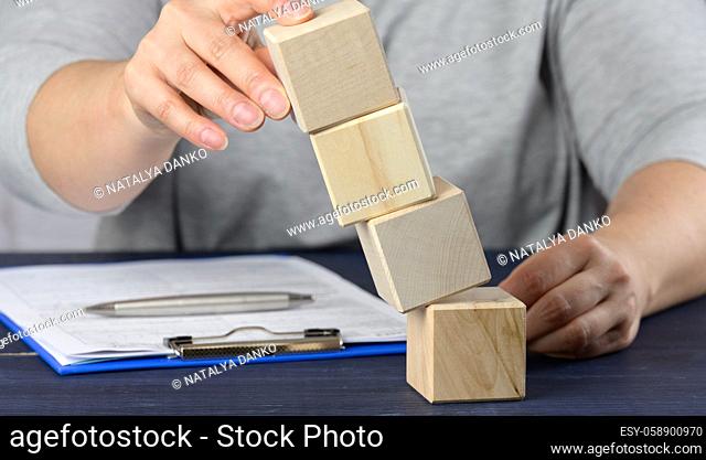 female hand holds falling cubes on the table. The concept of a manager's crisis, keeping the company afloat, stabilizing the enterprise
