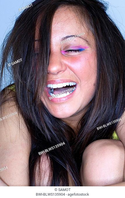 young woman with colourful eye makeup, laughing loudly