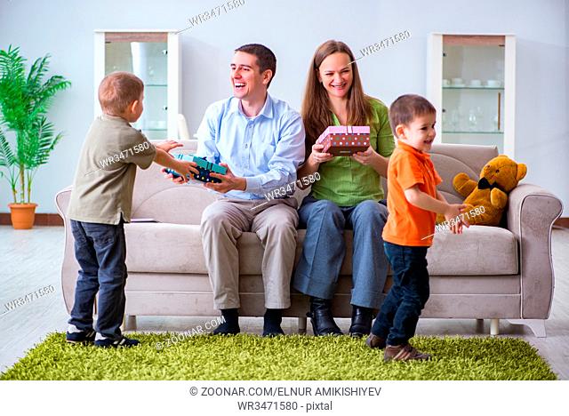 Young parents giving out Christmas gifts at home