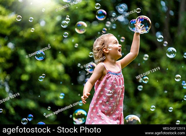Cheerful girl amidst bubbles at park