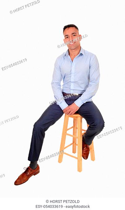 A happy east Indian man sitting relaxed on a chair taking a break, .smiling, in a blur dress shirt, isolated for white background