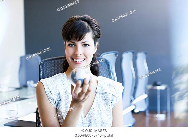 Businesswoman holding small globe in conference room