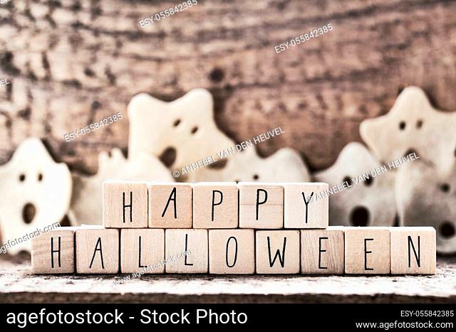 Words Happy Halloween on wooden cubes with group of scary ghost on wooden background, autumn mood horror halloween concept with witch hat modern design