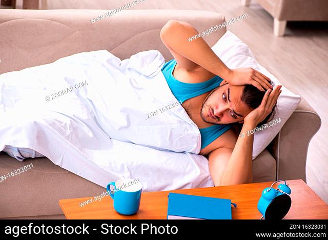 Young man lying on sofa in time management concept