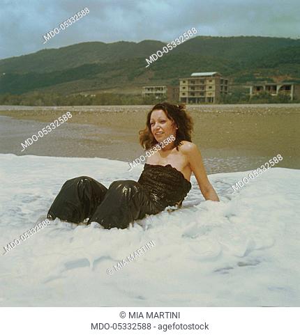 The singer Mia Martini (Domenica Rita Adriana Bertè) bathing at the sea with her clothes on. 1974