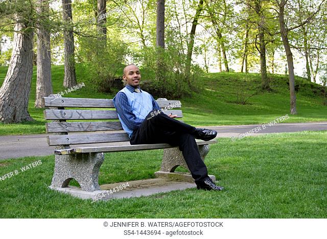 A young businessman sits on a park bench in Spokane, Washington, USA