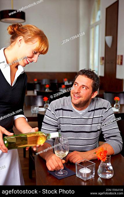 Kellnerin im Restaurant gießt Weißwein in ein Glas ein