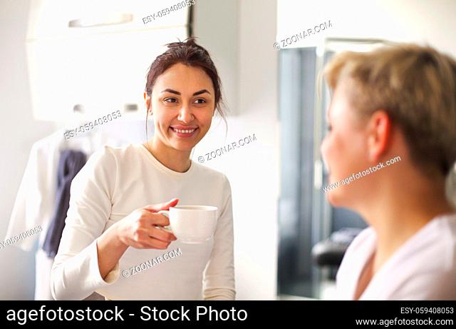 Female cosmetician with client drinkinh tea after skin care routine in salon