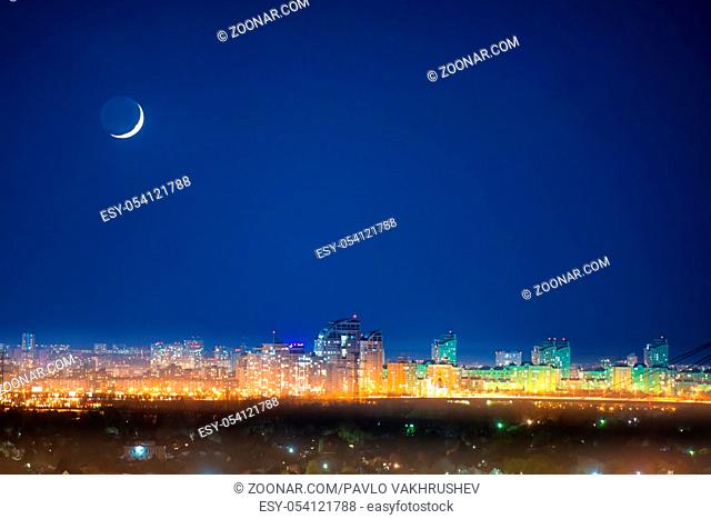 City at night with new moon on dark blue sky with stars