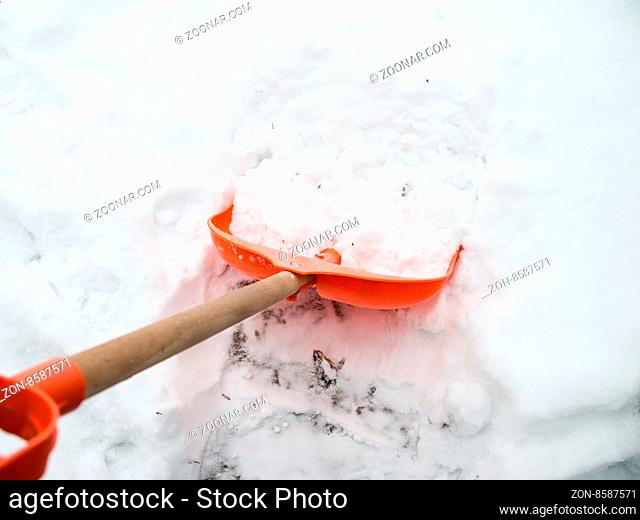 Snow removal. Orange Shovel in snow, ready for snow removal, outdoors