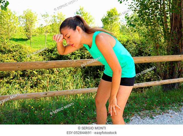 Woman bent over in exhaustion and catching her breath after a running session