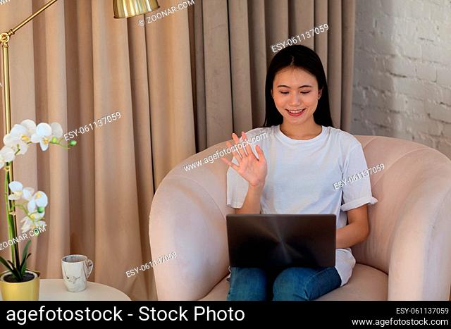 Portrait of asian woman enjoying using laptop at apartment interior indoor living room. Video call vlogger webinar stream concept
