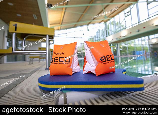 11 May 2021, Lower Saxony, Osnabrück: ILLUSTRATION - Two water wings and a swim board are lying on the side of the pool in the Moscaubad swimming hall