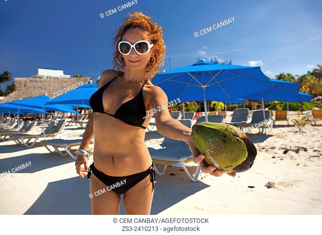 Woman holding a coco nut on the beach, Isla Mujeres, Cancun, Quintana Roo, Yucatan Province, Mexico, Central America