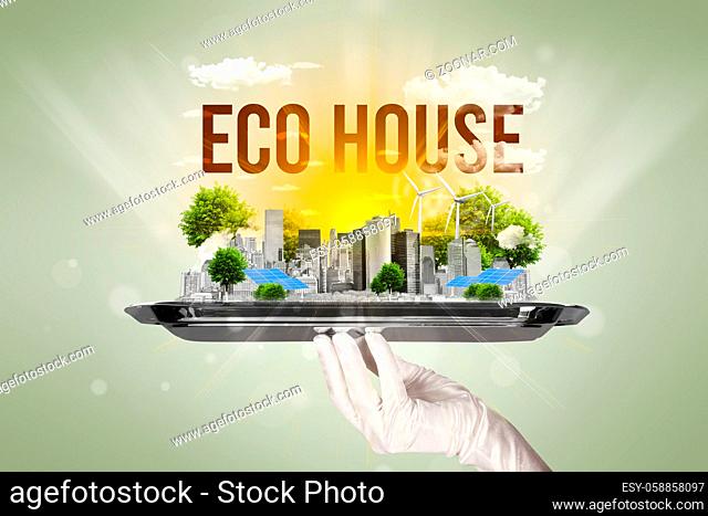 Waiter serving eco city with ECO HOUSE inscription, renewabke energy concept