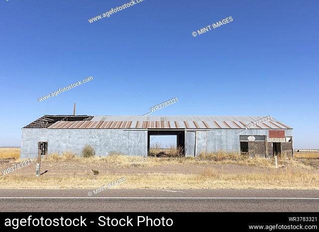 Abandoned rusting metal farm building with large open doors