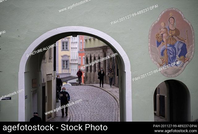 27 November 2020, Bavaria, Passau: People walk along the sidewalk of an alley at a distance. Passau imposes strict exit restrictions in view of the sharp...