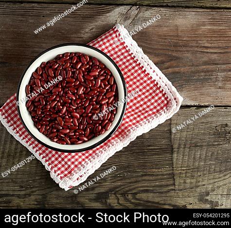 raw oval red beans in a plate on a wooden table. Organic meal. Vegetarian healthy natural food