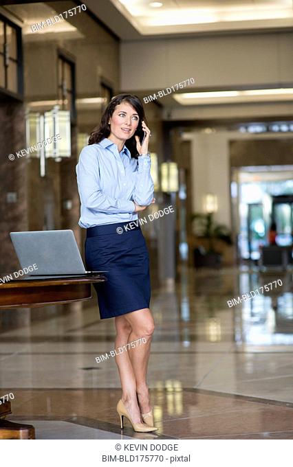 Caucasian businesswoman talking on cell phone in lobby
