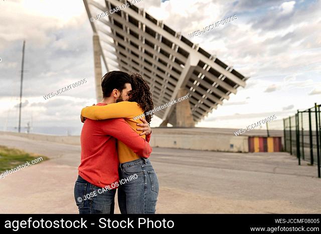 Happy couple hugging each other by solar panels