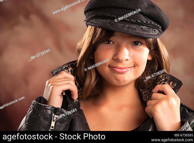 Pretty hispanic girl with hat and leather jacket studio portrait