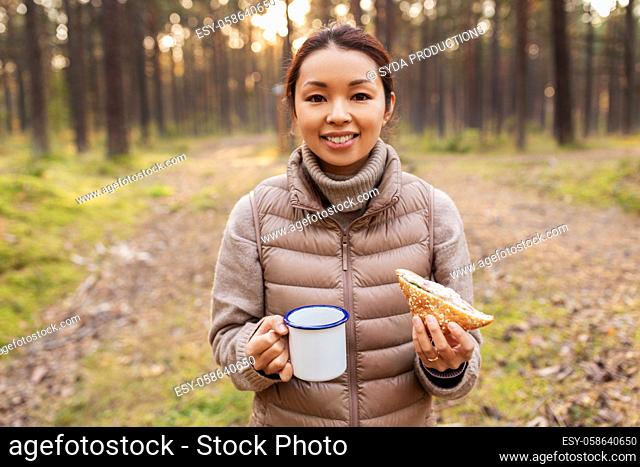 woman with mushrooms drinks tea and eats in forest