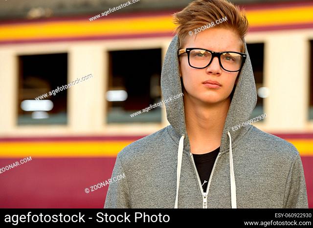 Portrait of young handsome teenage boy at the railway train station