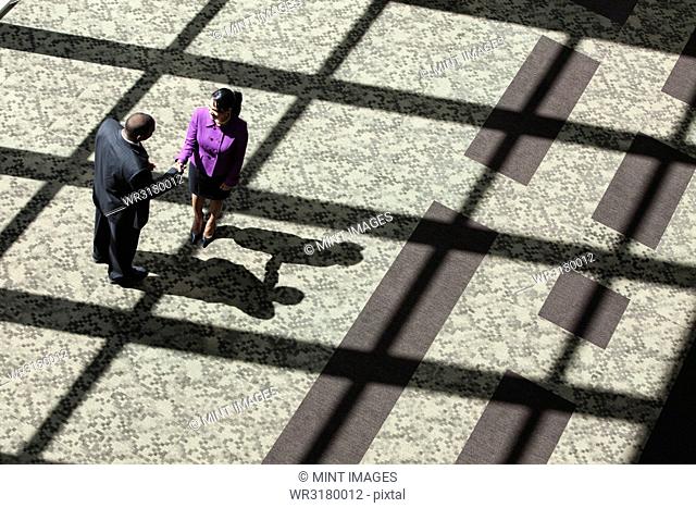 Black businessman and woman meeting in the lobby of a large business centre