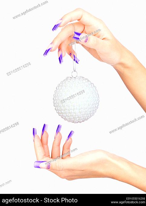 Hands with blue french false acrylic nails manicure holding perl christmas ball isolated on white background