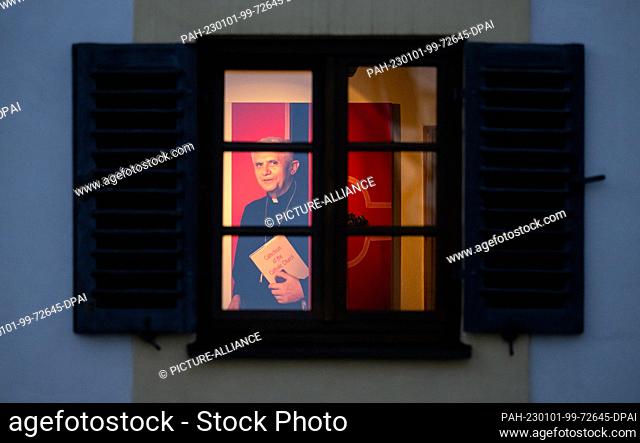 01 January 2023, Bavaria, Marktl: A photo of Pope Emeritus Benedict XVI is seen through a window in an exhibit at the birthplace