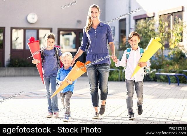 Mum and children with paper funnels for candy after first day at school