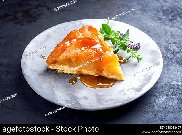 Traditional French tarte tatin with apples and vanilla offered as close-up on a modern design plate with rustic background