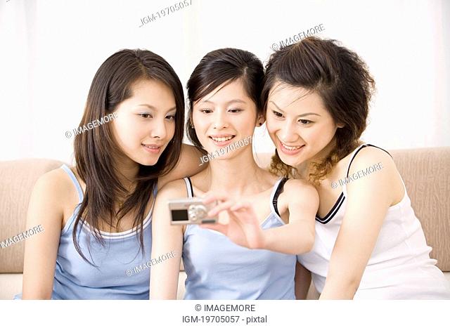 Three young women photographing themselves, smiling, portrait