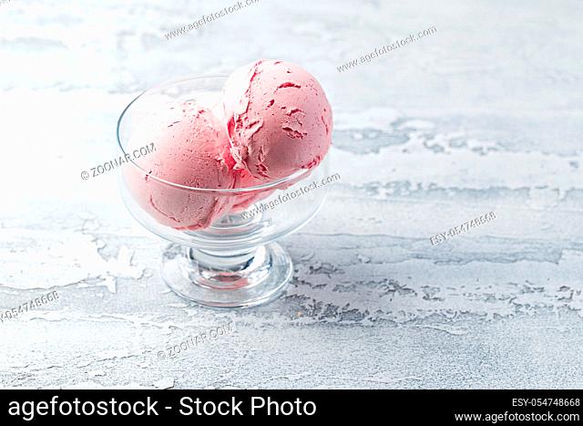 Glass bowl of pink ice cream on light background