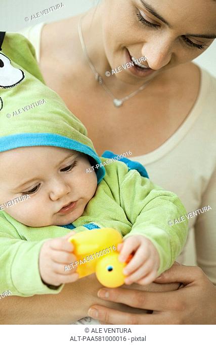 Mother and infant playing with rubber duck before bathtime