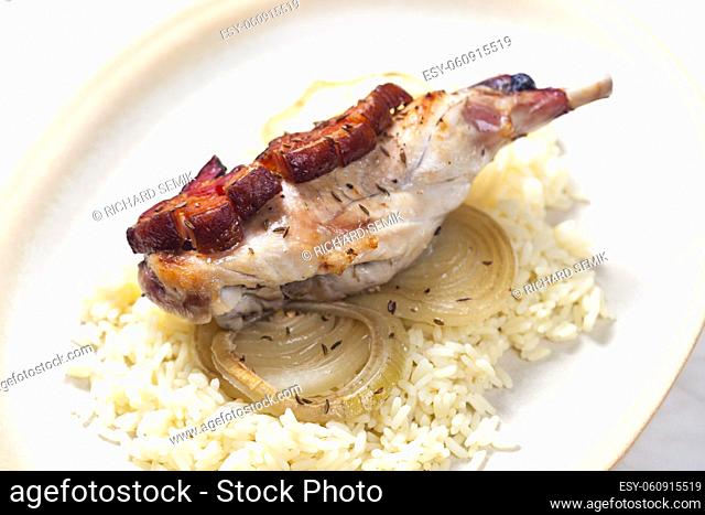 rabbit leg baked with bacon and onion served with rice