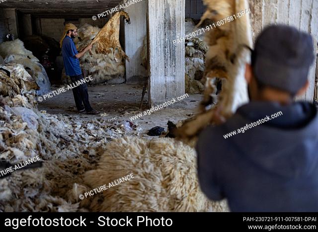 20 July 2023, Syria, Azmarin: Syrian workers prepare cattle hides for tanning and natural leather production at a workshop in the Syrian village of Azmarin