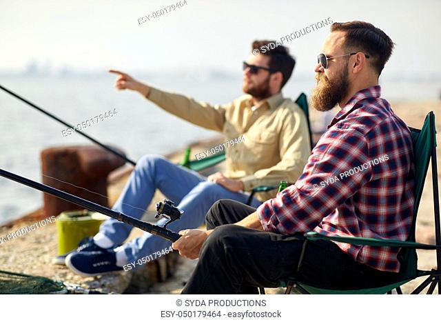 happy friends with fishing rods on pier