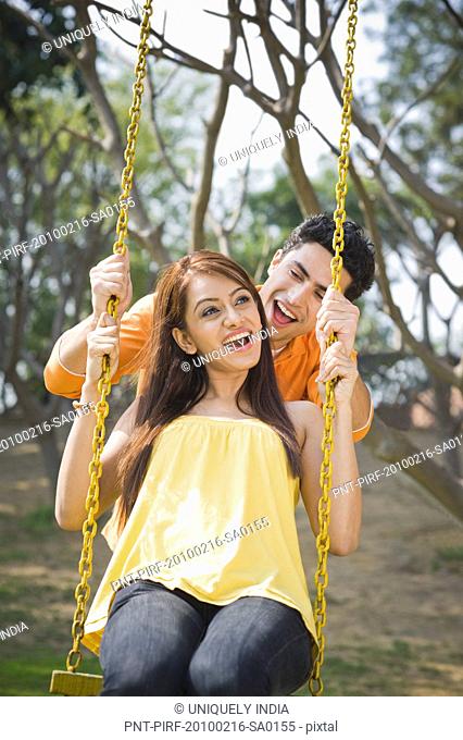 Man pushing a woman on a swing