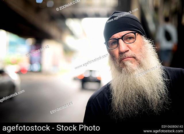 Portrait of mature handsome bearded hipster man in the city streets outdoors