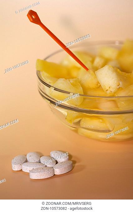 handful of pills and cup filled with pineapple slices concept of healthy nutrition and prevention medicine