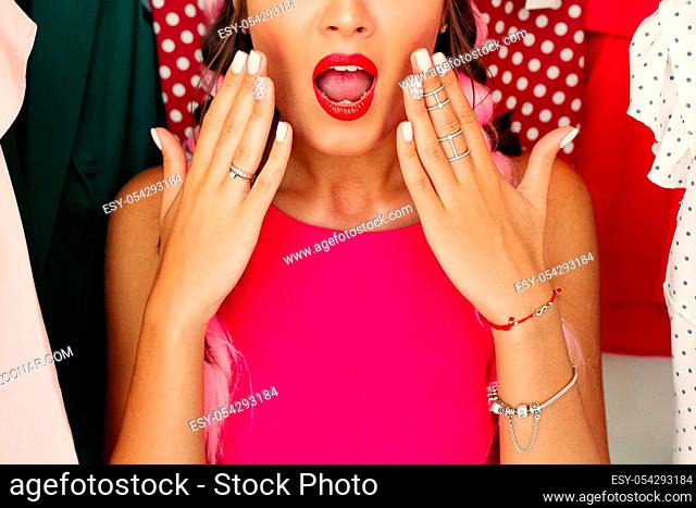 Crop, closeup portrait of young girl in pink blouse waching on camera and holding hands. Stylish, pretty, attractive woman confused of making decision