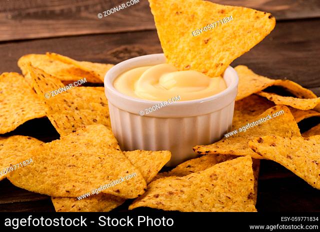 Nachos with cheese dip on an wooden table