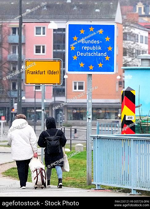 18 January 2023, Brandenburg, Frankfurt (Oder): Passers-by walking from the city bridge pass the yellow city entrance sign and the blue sign ""Federal Republic...