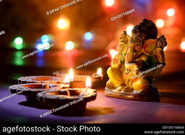 Clay diya lamps lit with Lord Ganesha during Diwali Celebration. Greetings Card Design Indian Hindu Light Festival called Diwali