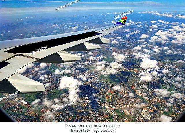 Wing of an Airbus in flight, with winglet and the logo of SAA, South African Airways, suburbs of Johannesburg at the back, South Africa