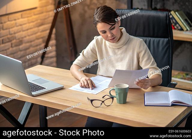 In the office. A woman sitting at the table in the office and working