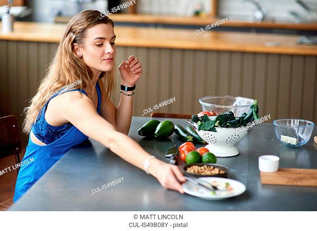 Young woman at kitchen table with finished salad plate